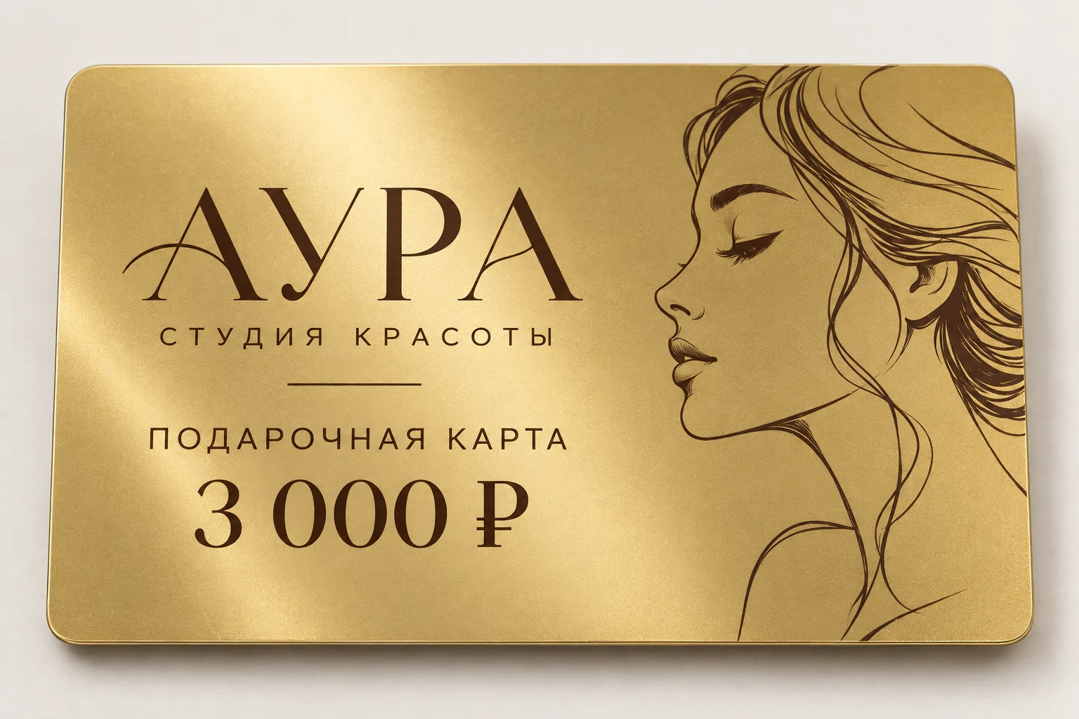 Золотой пластик крупным планом: подарочная карта студии красоты АУРА с тёмным рисунком и номиналом 3 000 рублей
